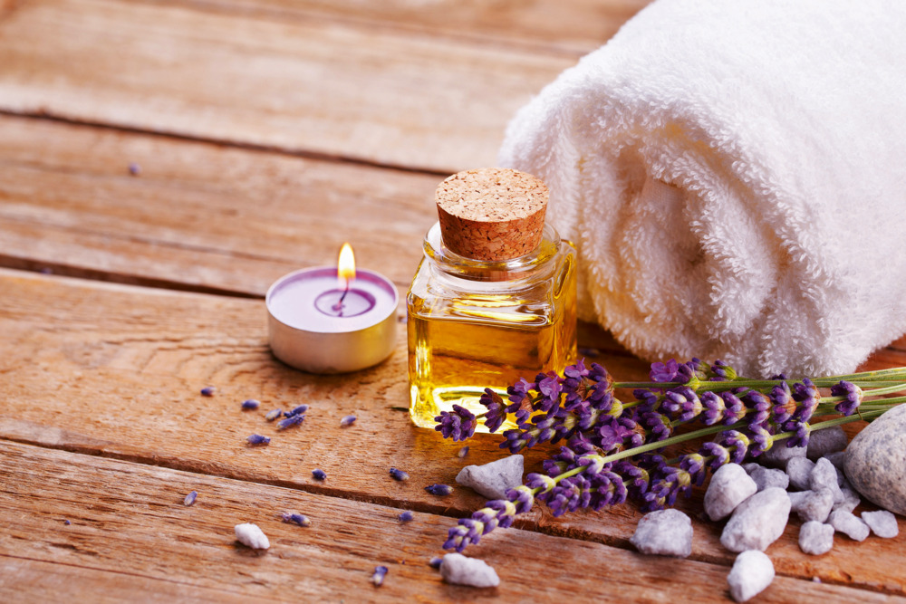 Spa still life with lavender oil, white towel and perfumed candle on natural wood